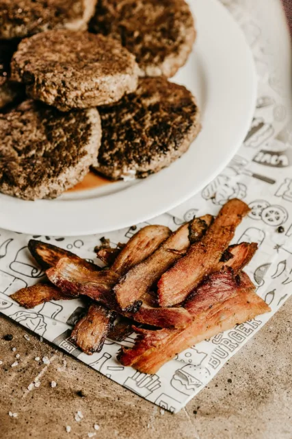 Photo by Jonathan Borba 1 a white plate topped with bacon next to a pile of cookies