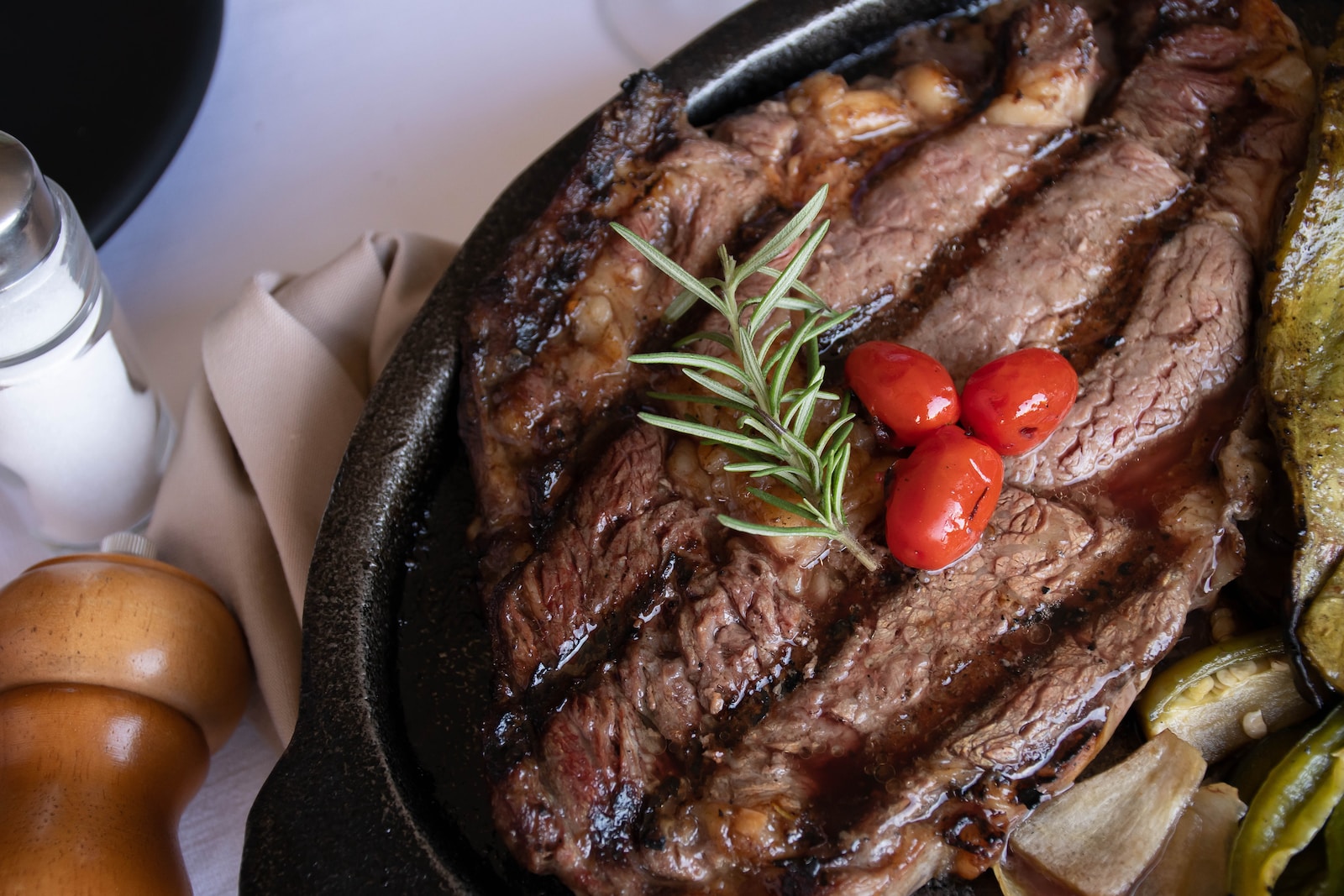 Photo by Gastro Editorial grilled meat with tomato and green vegetable on black pan