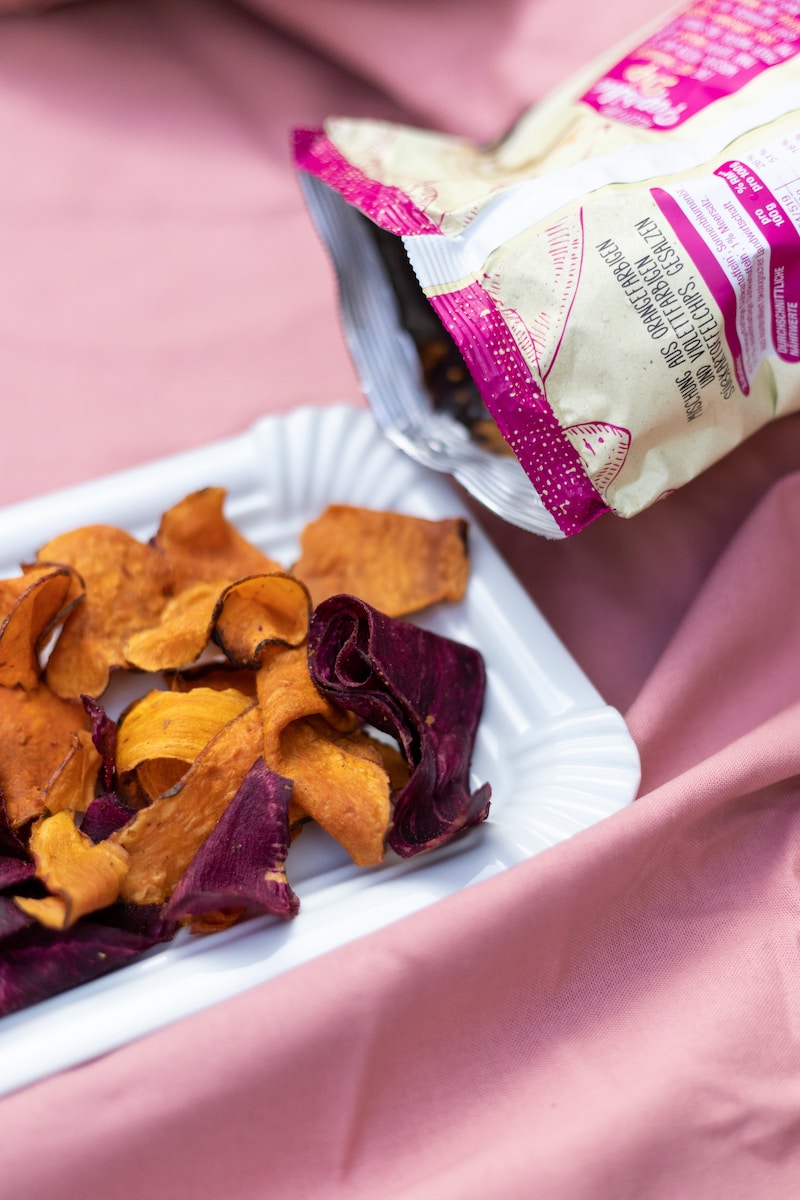 Photo by Yulia Khlebnikova a white plate topped with chips next to a bag of chips