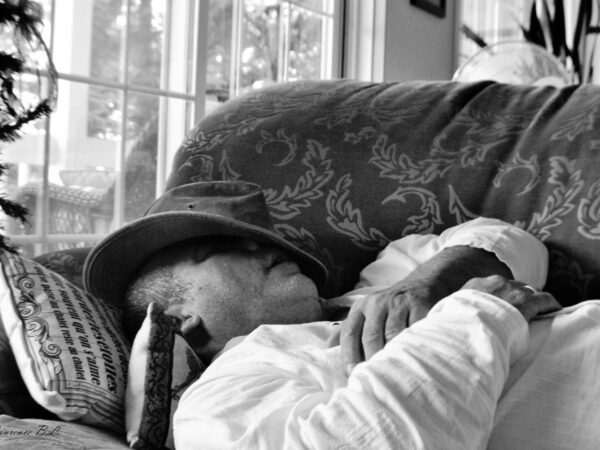 What Are The Habits That Ruin Your Sleeping? 22 a man sitting on a couch wearing a hat