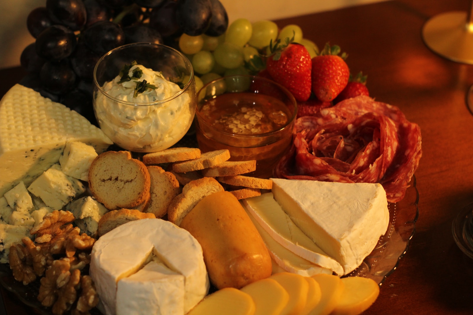 a platter of cheese, crackers, fruit and nuts